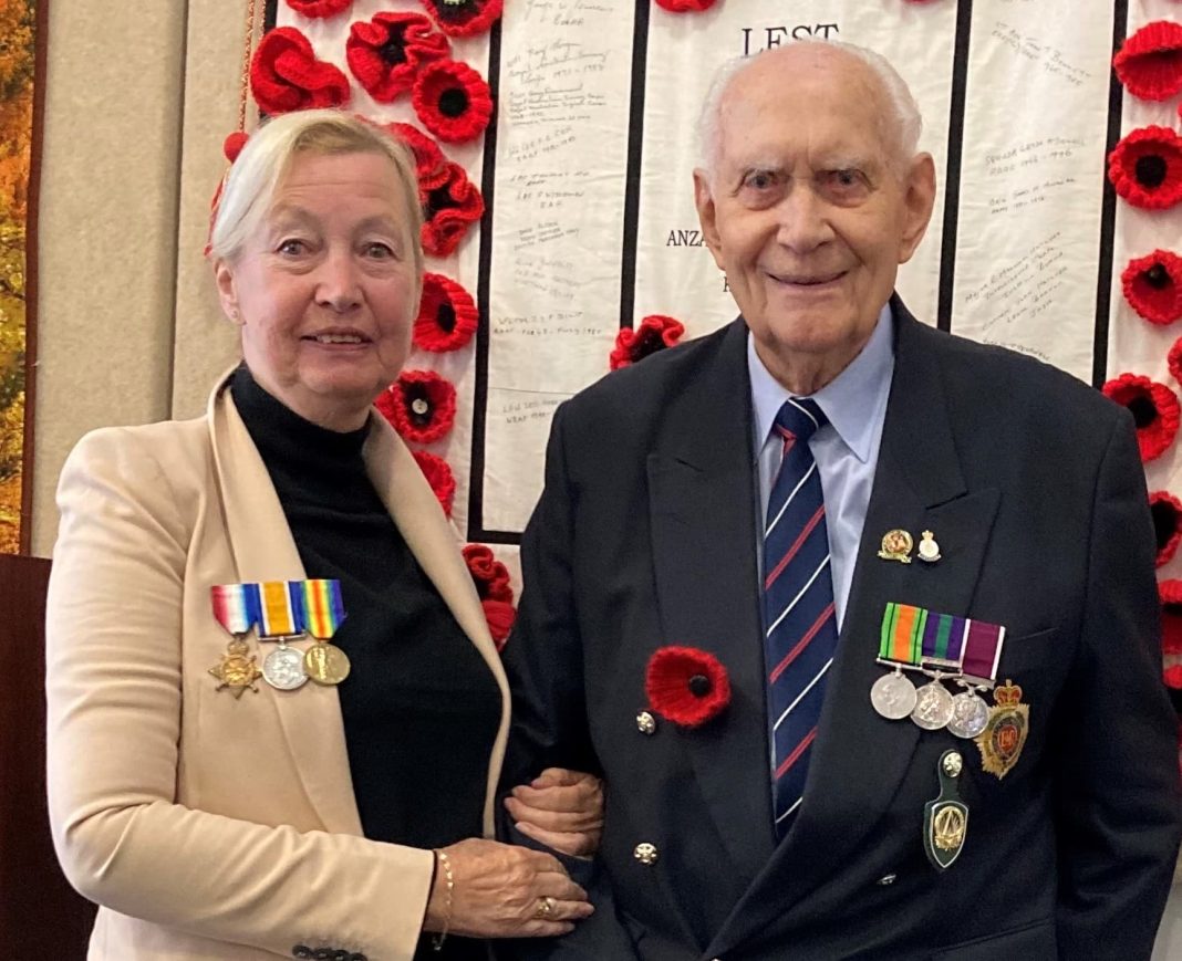 Elderly service man with medals standing with his daughter at an Anzac Day ceremony