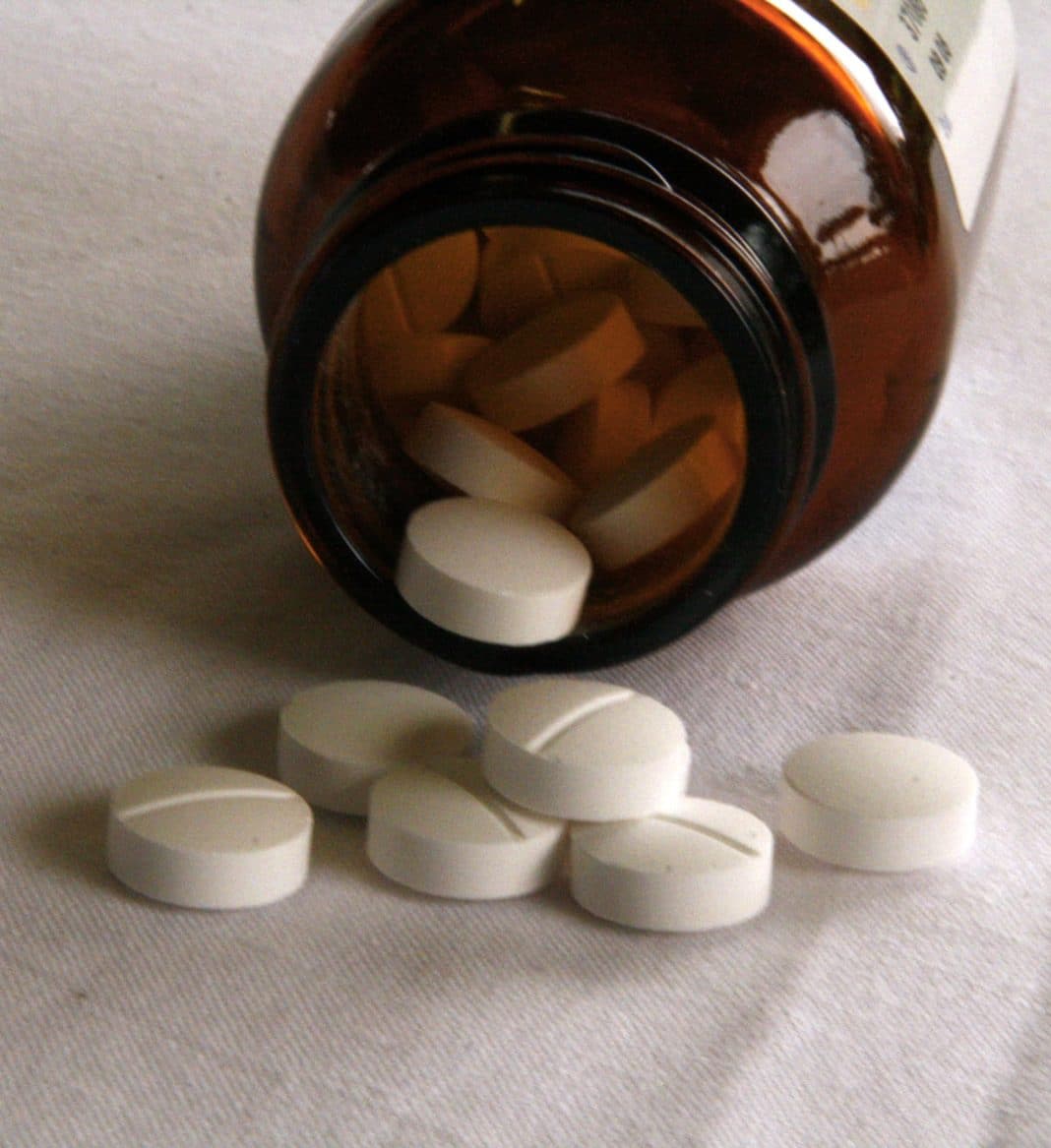 Tablets fall from a jar of medication