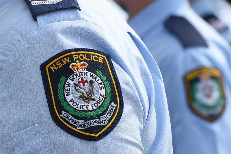 New South Wales Police badges are seen on blue shirt sleeves