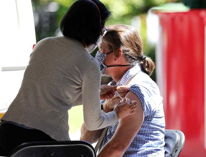 A nurse gives a woman a covid vaccination in her arm