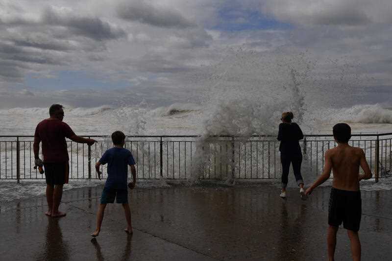 Onlookers watch as large waves pound the promenade and ocean baths at Bronte Beach in Sydney, Saturday, April 2, 2022