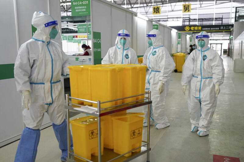 medical workers in protective suits walk at the Shanghai New International Expo Center, which has been converted to a quarantine facility for people with mild and asymptomatic cases of COVID-19