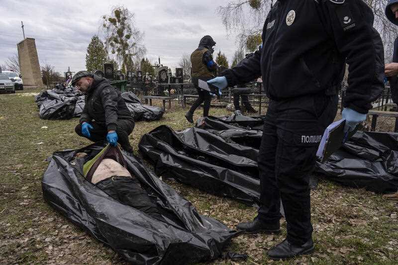 Police officers work in the investigation process following the killing of civilians in Bucha, before sending the corpses to the morgue, on the outskirts of Kyiv, Ukraine, Wednesday, April 6, 2022