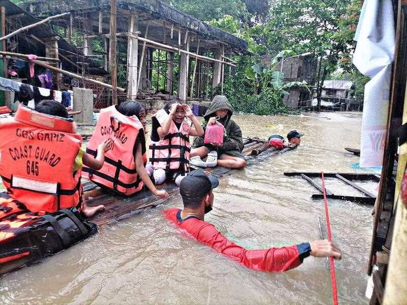 A handout photo made available by the Philippine Coast Guard (PCG) shows rescuers assist villagers in a raft in a flooded village in Panitan, Panay island, Philippines, 12 April 2022