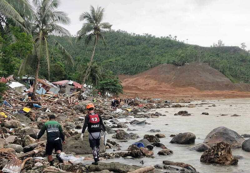 destroyed houses and a collapsed mountain side along the coastline in the landslide-hit town of Abuyog, Leyte island, Philippines