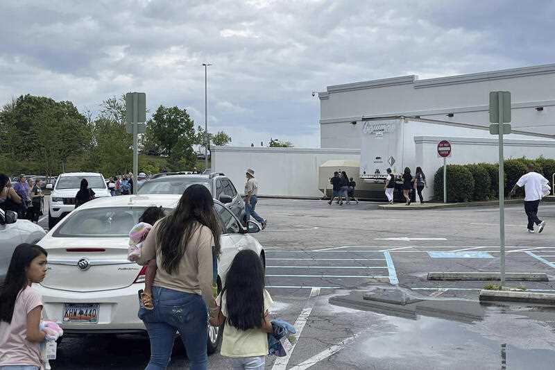 People walk through a parking lot at the Columbiana Centre mall in Columbia, S.C. on Saturday, April 16, 2022, as police investigate a shooting at the shopping center.
