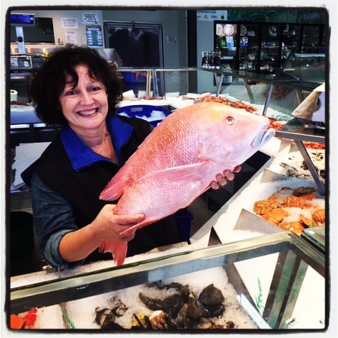 woman in fish shop holding a big fish