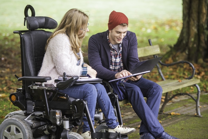 young man and his mum who is in a wheelchair, studying together at the park.