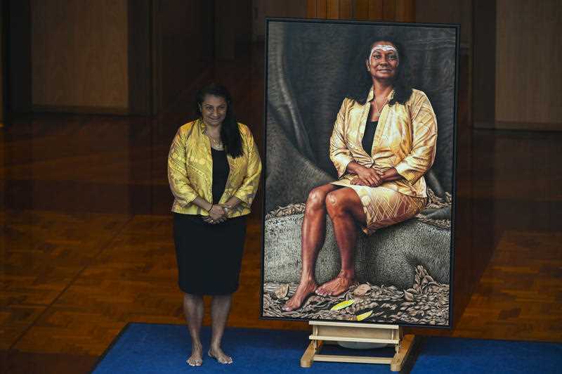 Former Labor senator Nova Peris poses for a photograph next to her official portrait at Parliament House in Canberra