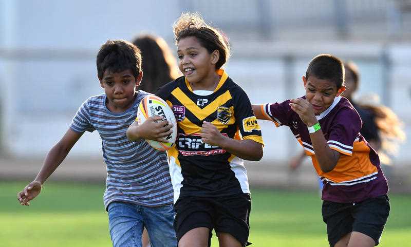 Young children are seen playing a game of Rugby League