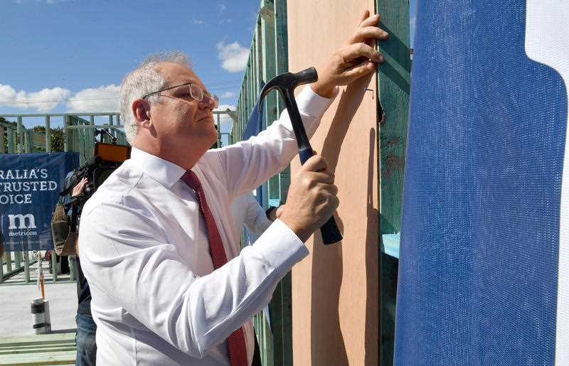 Scott Morrison is seen hammering a nail during a visit to a building site