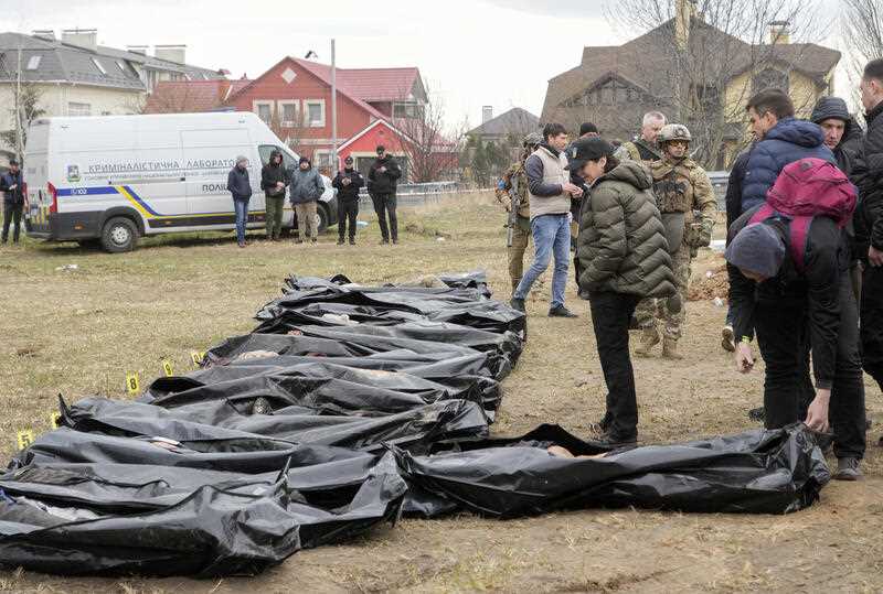 Ukrainian Prosecutor General Iryna Venediktova, center, looks at the exhumed bodies of civilians killed during the Russian occupation in Bucha, on the outskirts of Kyiv, Ukraine, Friday, April 8, 2022.