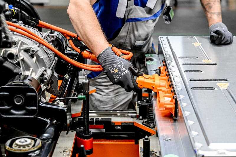 A Volkswagen employee works on on a electric cars assembly line at an electric vehicle factory