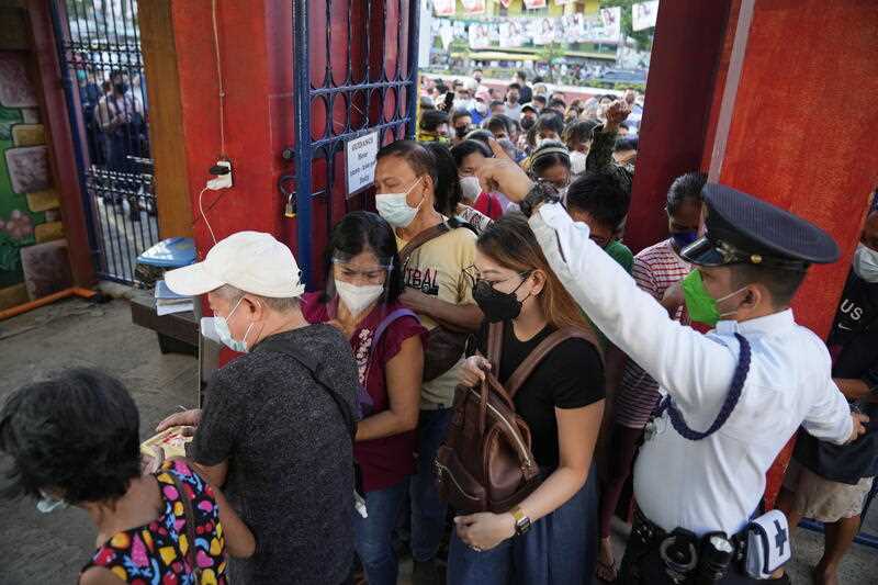 People rush to enter a school used as a polling center to vote during the opening of elections on Monday May 9, 2022 in Quezon City, Philippines.