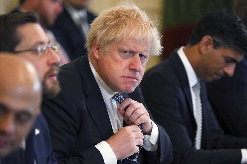 Britain's Prime Minister Boris Johnson adjusts his tie at the start of a cabinet meeting at 10 Downing Street, London, Tuesday May 24, 2022