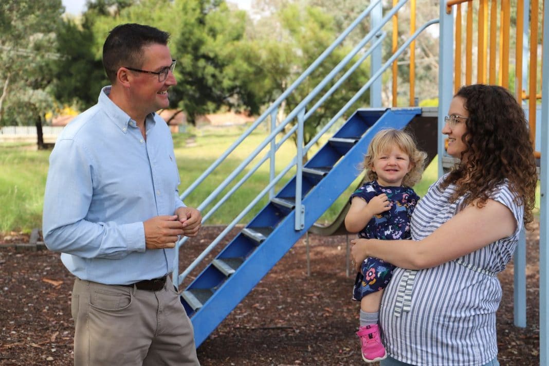 Liberal Senator for the ACT Zed Seselja talking to a mum holding a toddler in a playground