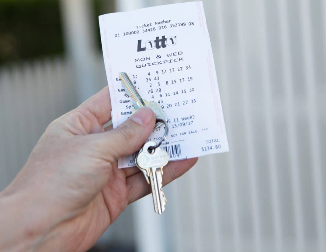 hand holding quick pick lotto ticket and house keys