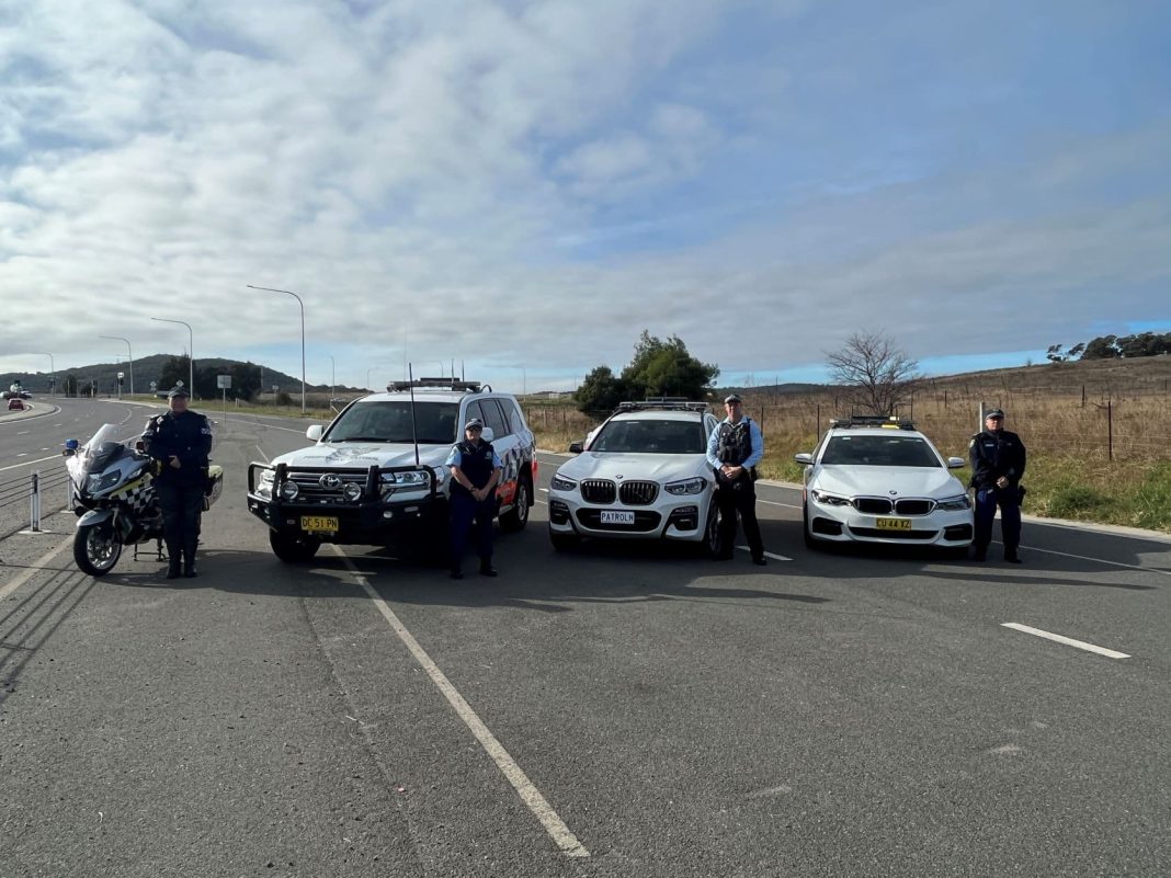 4 police officers and vehicles - 2 each from ACT and NSW - lined up on a parking bay beside the Monaro Highway
