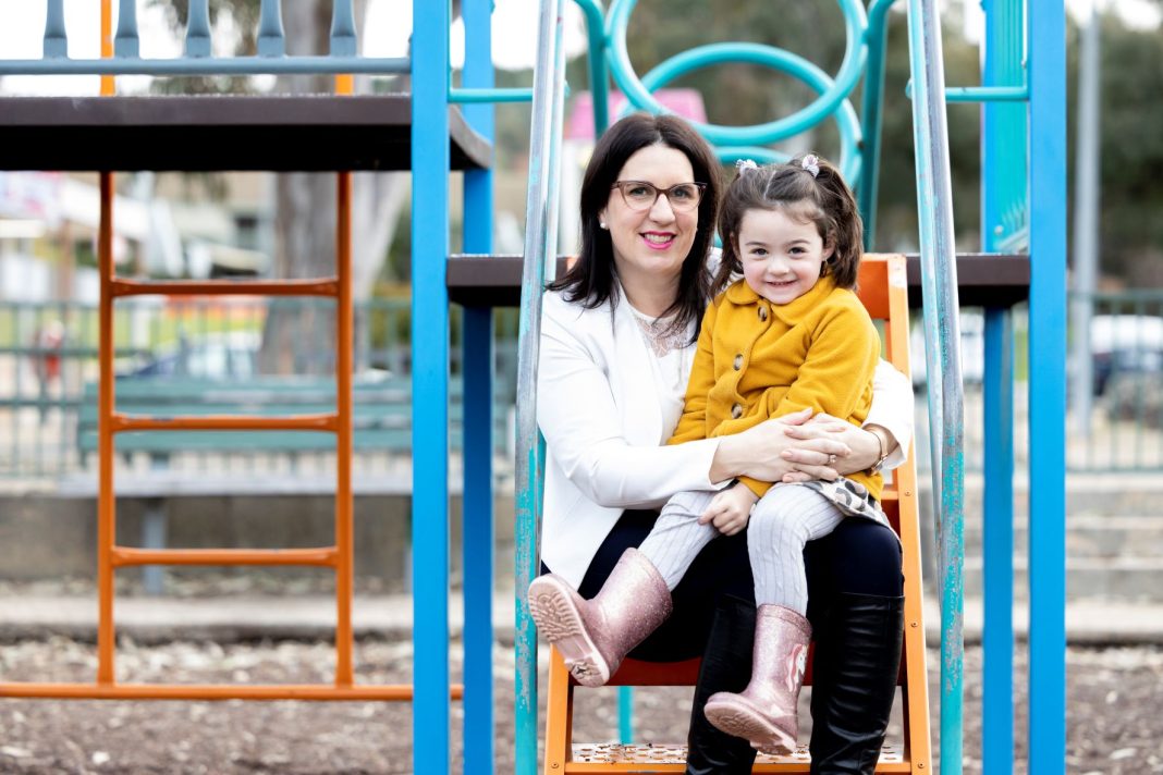 woman and young daughter sitting in a playground