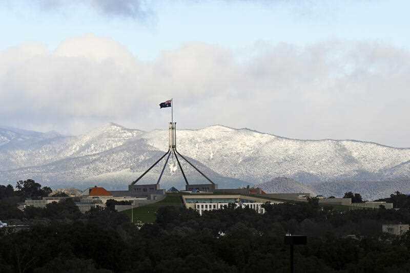 Snow covered hills are seen behind Parliament House in Canberra, Wednesday, June 1, 2022.