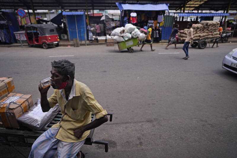 A labourer drinks tea at a market place in in Colombo, Sri Lanka, Friday, June 10, 2022