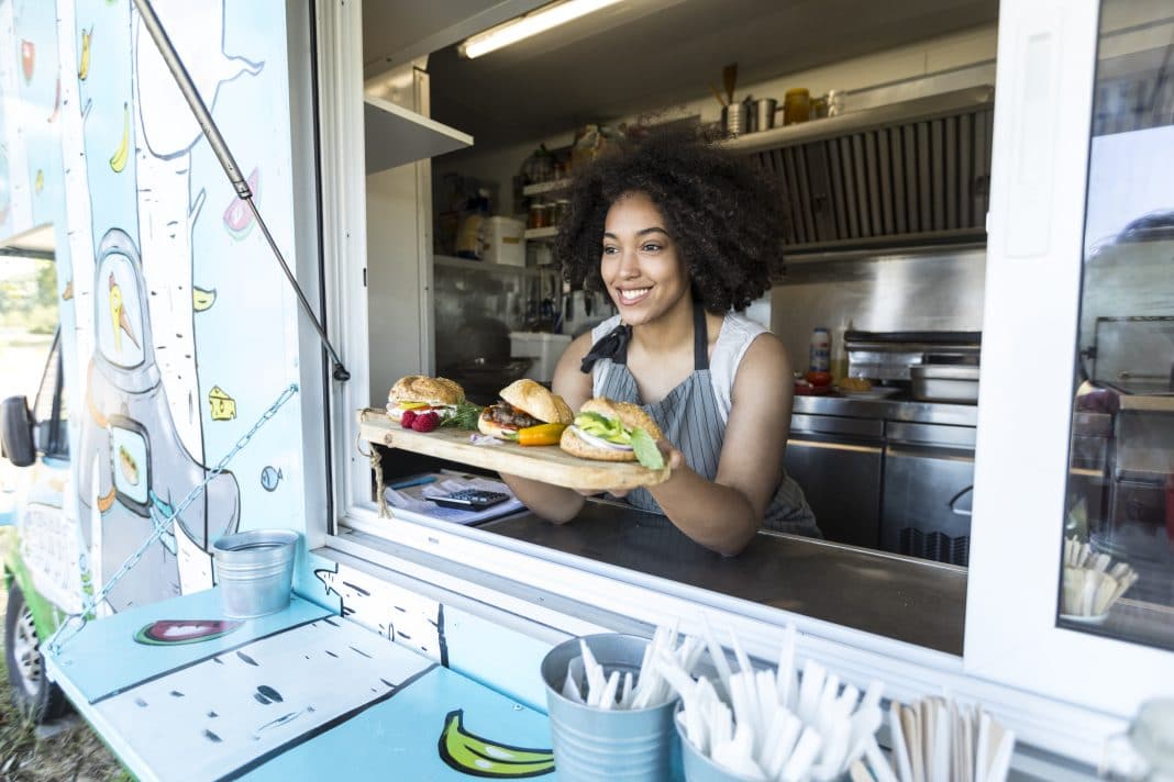 Female food vendor offering sandwiches in food van