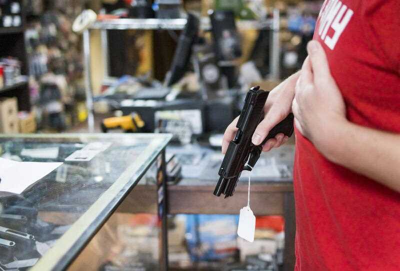 A male customer holds a handgun for sale at the NY Shooter Supply gun shop in Albany, New York, USA