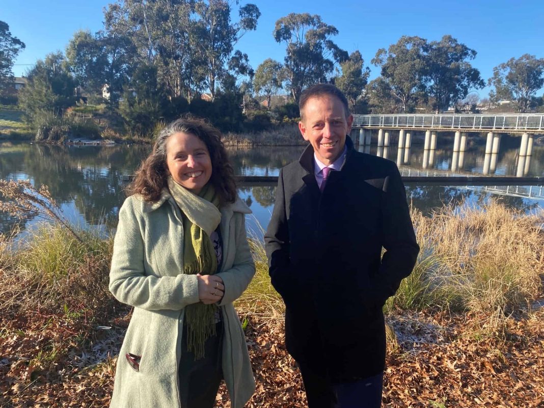 1 female and 1 male ACT Greens politicians standing beside a weir