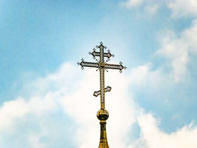 Orthodox church cross on a background of blue sky with clouds.