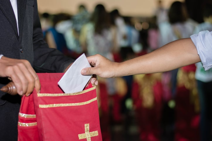 person putting tithing into Velvet offering bag in church